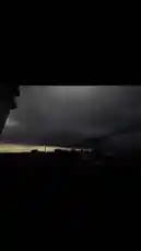 A dramatic, low-light landscape shot captures a vast, overcast sky filled with dark, brooding clouds. Silhouettes of power lines and distant buildings stretch across the horizon, creating a moody and atmospheric scene. The camera pans slowly, emphasizing the scale of the ominous weather and the quiet stillness of the environment. by @mrsahir00 with Original Sound by mrsahir00