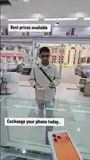 A customer completes a phone exchange deal at محل السوبر الذهبي للهواتف. A store employee hands over a new orange Honor phone while the customer receives cash and their old device. The transaction takes place at a glass counter, with promotional signs for 'Best prices available' and 'Exchange your phone today..' visible in the background. by @super_golden7 with Original Sound by super_golden7
