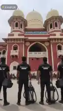 A group of four cleaners from the brand '100SERVICE' stand in formation in front of the iconic Kanpur Central railway station. Dressed in matching black uniforms with white gloves, they perform a synchronized arm-raising routine while holding professional cleaning equipment, showcasing their team spirit and service pride. by @in.100service with in.100service by Original Sound