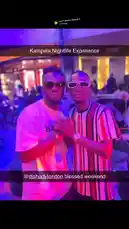 This static image captures a moment from Gxcci Outta Here's nightlife experience. He poses with a friend in a vibrant, purple-lit lounge or nightclub. Both men are stylishly dressed and wearing sunglasses, creating a cool, social atmosphere. The image suggests a fun night out, perfect for fans looking for a glimpse into his life. by @managergxcci with can't leave without it by 21 Savage