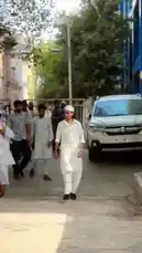 A group of young men dressed in traditional white clothing walk down a street. One man in the center stops to pose for the camera. by @lil.ishhhh with Original Sound by lil.ishhhh