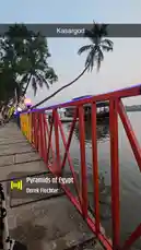 This short clip captures a peaceful evening stroll along the riverbank in Kasaragod. The camera moves along a vibrant red and yellow railing, showcasing the calm water, lush palm trees, and a traditional houseboat docked nearby. It's a tranquil scene of local life and natural beauty. by @super_golden7 with Pyramids of Egypt by Derek Fiechter
