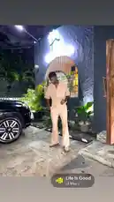 This short clip captures Nigerian artist Delly in a moment of relaxed style. He stands confidently in a cream-colored jumpsuit on a stone-paved driveway at night, next to a sleek black car. The scene is illuminated by warm lights from a building entrance, creating a chic and atmospheric vibe. by @delwinbazilme with Life Is Good by Lil Man J