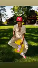 Watch Delly showcase his latest streetwear look in a stunning outdoor setting. This static shot captures him sitting on a bright yellow block, modeling a beige outfit, red 'Jordans' cap, and iconic red-and-white checkerboard Vans sneakers. The vibrant colors pop against the lush green lawn and rustic cabin backdrop, creating a perfect aesthetic for summer fashion inspiration. by @delwinbazilme with I Just Wanna Know (feat. Ty Dolla $ign & Cardi B) by Nipsey Hussle, Bino Rideaux