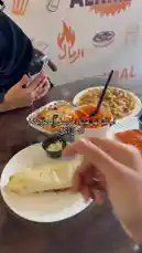 A close-up look at a delicious meal from Al Ramal restaurant, featuring a fresh wrap, cheesy baked dish, and vibrant orange rice. Watch as we enjoy our food together. by @sandshawarma with Original Sound by sandshawarma