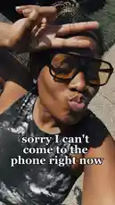 A close-up selfie video of UniquePearlz outdoors on a sunny day. She playfully poses for the camera, making a 'busy' hand gesture over her eyes while wearing large sunglasses. Text overlays humorously state, 'sorry I can't come to the phone right now' and 'I'm a little bit busy with girl therapy,' before she looks at the camera and says, 'maybe!' The scene captures a lighthearted moment of self-care and setting boundaries. by @uniquepearlz with uniquepearlz by Original Sound