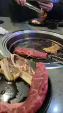 dassweenbean 님이 만든 Original Sound 포함 @dassweenbean 님이 만든 A close-up, mouth-watering view of a sizzling Korean BBQ grill. Fresh marinated beef and pork belly are being cooked on the hot surface, showcasing the delicious process of preparing this popular meal.