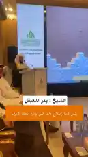 In a formal lecture setting, speaker Yaser Al-Khamsan stands at a podium addressing an audience. A large screen behind him displays his portrait alongside Arabic text, including the phrase 'the foundation of happiness and well-being.' His speech, delivered in Arabic, emphasizes the importance of good character ('الأخلاق الجميلة') as a key component of happiness. by @y_alkhmsan with Original Sound by y_alkhmsan