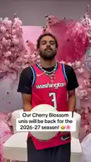 A player from the Washington Wizards team presents the new Cherry Blossom uniform design for the upcoming 2026-27 season. Dressed in the red jersey with the number 3, he stands before a backdrop of pink cherry blossom trees and umbrellas, holding a basketball. A text overlay confirms the return of these special edition jerseys. by @washwizards with original sound