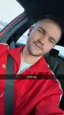 A man identified as Kenneth sits relaxed inside a car, wearing a vibrant red Adidas jacket over a white shirt. He looks directly at the camera with a calm expression, capturing a candid moment of leisure. The text overlay 'Chill day' reinforces the laid-back theme. The scene is static, focusing on his appearance and the casual atmosphere. by @ken_sutton23 with original sound