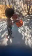 A heartwarming scene unfolds in a sunny backyard where young children are joyfully playing with basketballs. One child, shirtless and wearing patterned shorts, dribbles a ball with enthusiasm while another child joins in the fun. They pass the balls back and forth, showcasing their playful energy and coordination. The setting includes a wooden fence, a garage door, and a bicycle parked nearby, creating a typical suburban home environment. This lively moment captures the innocence and excitement of kids enjoying outdoor playtime together. by @marcus.randall with Original Sound by marcus.randall