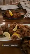 오리지널 사운드 포함 @itsma_bitchezz 님이 만든 This video captures a mouthwatering seafood spread at Papa Joe's Waterfront, featuring golden-brown fried shrimp and calamari garnished with lemon wedges. The cozy restaurant setting, complete with wooden tables and a menu in view, creates an inviting atmosphere perfect for enjoying a delicious meal.