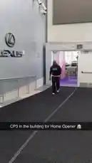 A man wearing a brown hoodie with 'Plant-Based Essentials' text walks through a doorway into a room with purple carpeting inside a building prominently displaying the Lexus logo. by @clippers with Original Sound by clippers