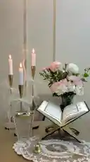 This serene video captures a peaceful morning ritual perfect for starting the week. It features a beautifully arranged table with an open Quran on a wooden stand, three lit white candles in elegant gold holders, and a vase of fresh pink and white flowers. Soft, gentle music plays as Arabic text overlays appear sequentially, offering a heartfelt prayer for the week ahead. This calming visual is ideal for those seeking inspiration for their daily spiritual practice. by @semsemallc25 with Original Sound by semsemallc25