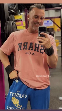 In this energetic gym selfie, fitness influencer Mark The Shark shows off his workout look and shares a moment from his active lifestyle. Wearing a 'Shark & Co.' t-shirt and blue track pants, he captures a candid, smiling moment during a night out at the gym. The casual yet confident vibe highlights personal branding and daily motivation. by @mts550 with original sound