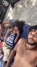 This vlog-style video captures a relaxed summer day with family and friends. It begins with a man and a young boy lounging on a blue towel outdoors. The scene then shifts to a view from inside an inflatable structure, looking up at a bright blue sky with clouds, trees, and a basketball hoop visible through the mesh walls. by @marcus.randall with Summertime by DJ Jazzy Jeff & The Fresh Prince