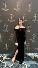 Watch Kastiela Garcia confidently pose on the red carpet at the Miss Multicultural USA event. She wears a stunning black off-the-shoulder gown with a thigh-high slit and delicate white heels, showcasing her elegance against the official backdrop. by @kastielagarcia with kastielagarcia by Original Sound