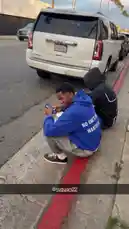 In this short clip, Jeremiah Brown is seen sitting on a red curb with friends. He suddenly stands up and runs away after being startled, suggesting a surprise prank or playful chase. The scene captures a candid moment of street life and friendship. by @findjeremiah with Original Sound by findjeremiah