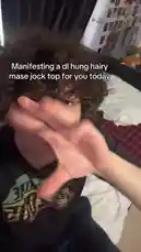 In a playful and energetic display, Evan performs a 'manifestation' ritual, waving his hand in front of the camera while text on screen reads 'Manifesting a dl hung hairy mase jock top for you today.' The scene captures a moment of lighthearted self-expression and humor. by @evanjakeof with Original Sound by evanjakeof