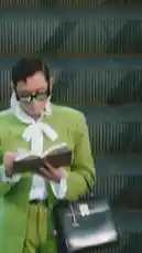 A man in a vibrant green suit and white bow tie explores the modern architecture of Westfield Century City. He reads a book, walks through the shopping center, and rides an escalator, all while stylishly carrying a black briefcase. The journey is set against a backdrop of sleek glass and steel, capturing a moment of urban sophistication. by @specs with Original Sound by specs