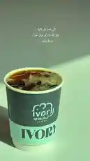 A beautifully lit close-up of a branded Ivory coffee cup filled with iced coffee, set against a minimalist background. Overlaid with elegant Arabic calligraphy poetry, the scene evokes a serene, artistic mood. This visual collaboration blends modern aesthetics with cultural expression. by @batoolmakeup1 with original sound