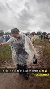A woman in a clear poncho dances joyfully in a muddy field during a rainy festival. She smiles and moves her arms to the music, surrounded by other attendees enjoying the event despite the wet weather. by @snapcreators with Original Sound by snapcreators