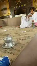 مناحي الرجباني يجلس على أريكة في غرفة مزينة بأسلوب فاخر، يرتدي الزي الأبيض التقليدي ويستمتع بشاي صغير. تظهر في الخلفية نوافذ وديكورات ذهبية، ثم ينهض من الأريكة ويتوجه نحو النافذة. المشهد يعكس جواً من الراحة والهدوء. by @manahi.20 with manahi.20 by Original Sound