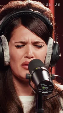 Watch Sienna Spiro deliver a heartfelt performance of her song 'Pun' in a minimalist studio setting. Wearing headphones and singing into a professional microphone, she conveys deep emotion through her expressive face and powerful vocals. The intimate atmosphere, highlighted by warm lighting and a glowing neon sign, captures the essence of a modern acoustic music session. by @geniusverified with Original Sound by Contains: Pure - SIENNA SPIRO