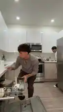 In a modern kitchen, a man is seen loading a dishwasher when another person suddenly enters the frame. The first man turns around with a startled expression, prompting a playful shout from the second person, creating a comedic moment. by @twinksebass with Original Sound by twinksebass
