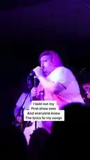 Witness the raw emotion and triumphant moment as musician TALK celebrates selling out their very first show. Bathed in purple stage lights, they sing passionately into the microphone, arms raised to the adoring crowd who know every word. This powerful performance captures the feeling of achieving something special. by @iamtalk with iamtalk by Original Sound