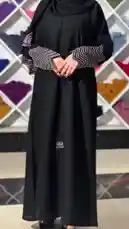 A woman models a stylish black abaya with distinctive patterned sleeves in a modern retail setting. She holds a branded shopping bag from 'Khial Abaya' while posing, showcasing the garment's design and fit. by @mohammed_aldrop with Original Sound by mohammed_aldrop