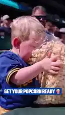 A heartwarming moment captured at a baseball game shows a young child in a blue jersey enthusiastically eating popcorn straight from a large bag. This candid scene perfectly encapsulates the fun and excitement of attending a live MLB event. by @mlb with Original Sound by mlb