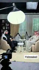 In this exclusive behind-the-scenes look, Dr. Mohammed Al-Margoub, a prominent plastic surgeon, is featured in a professional studio setting during an interview. The scene captures him seated comfortably in a modern armchair alongside another individual, engaged in conversation under bright studio lighting. The camera setup, including a large softbox light and a DSLR on a tripod, highlights the production quality of his content. This clip offers viewers insight into the creation process of educational and promotional material by a leading figure in the field of cosmetic surgery. by @dralmarghoub with original sound