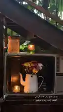 A beautifully styled vintage television set is repurposed as a display for a charming flower arrangement in a white pitcher and flickering candles. The scene is warmly lit, creating a cozy and nostalgic atmosphere perfect for home decor inspiration. by @batoolmakeup1 with ❤️❤️⏳. by Angham✨