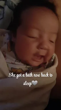 A close-up shot captures a baby's wide-eyed, curious expression as they react to something off-camera. The intimate, dimly lit scene highlights the baby's innocent wonder, creating a heartwarming moment. by @alonamia22 with Original Sound by alonamia22