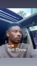 In this short clip, rapper Delly shares a moment from his day. He is seen sitting in the driver's seat of a car with the sunroof open, looking out thoughtfully. The text overlay '10:10 PM Sante Domingo' suggests he is reflecting on his evening in the Dominican Republic. This personal snapshot captures a quiet, contemplative mood. by @delwinbazilme with Ramen & OJ by Joyner Lucas, Lil Baby