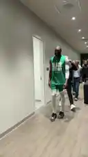 A Boston Celtics player walks through the team's locker room, greeted by teammates. The atmosphere is focused and professional as players prepare for the game. by @celtics with Original Sound by celtics