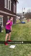 Watch Chris Colditz in a vibrant pink shirt and red shoes as he sprints across a lush green lawn towards a wooden obstacle structure. In the background, another person stands ready on a platform, while a third individual films the action near a brick building. This energetic outdoor scene captures the fun of backyard challenges and active play. by @chriscolditz with Original Sound by chriscolditz