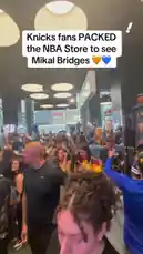 A packed crowd of New York Knicks fans gathers inside the NBA Store for a meet-and-greet event featuring star player Mikal Bridges. The video captures the excitement of the moment as Bridges signs autographs on jerseys and interacts with his supporters. The atmosphere is electric with anticipation, showcasing the strong connection between the player and the fanbase. by @yahoosports with Original Sound by yahoosports