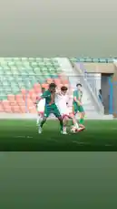 This dynamic clip captures a key moment during a football match involving Saudi Arabia's Al-Rawdah Club. Players in green and white kits battle intensely for control of the ball on a well-maintained pitch, showcasing the competitive spirit of local sports. The scene unfolds under bright daylight in a stadium with colorful seating, emphasizing the energy of grassroots football in Saudi Arabia. by @alrawdahclub with original sound