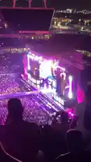 brattyluhbaby 님이 만든 Original Sound 포함 @brattyluhbaby 님이 만든 An energetic night concert featuring Sabrina Carpenter performing live on a massive stage filled with dazzling lights and pyrotechnics. The crowd is packed into a large stadium, creating a vibrant atmosphere under the city skyline.