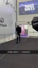 A man dressed in all black confidently walks through a modern building lobby towards the camera. He passes by prominent Lexus branding and a large screen displaying 'MAKE WAVES'. As he approaches, he reaches out and opens a glass door, revealing more of the event space beyond. by @clippers with Original Sound by clippers