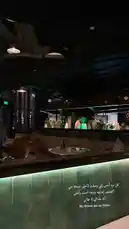 This stylish interior shot captures the ambiance of a modern lounge or restaurant at night. The scene features chic seating with a glowing green marble accent wall, contemporary pendant lighting, and a bar area in the background, all contributing to a sophisticated and inviting atmosphere. by @batoolmakeup1 with ✨✨✨✨ by Rwn