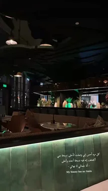 This stylish interior shot captures the ambiance of a modern lounge or restaurant at night. The scene features chic seating with a glowing green marble accent wall, contemporary pendant lighting, and a bar area in the background, all contributing to a sophisticated and inviting atmosphere. by @batoolmakeup1 with ✨✨✨✨ by Rwn
