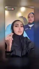 This behind-the-scenes look at Bella Clinic offers a personal perspective on a beauty treatment. A woman in a black hijab and protective gown is the central focus, while another staff member in a blue uniform observes her process. The setting appears to be a professional clinic room, suggesting a skincare or aesthetic procedure. The accompanying Arabic dialogue indicates a conversation about the treatment, enhancing the authentic feel of the experience. by @bellaclinickw with Original Sound by bellaclinickw