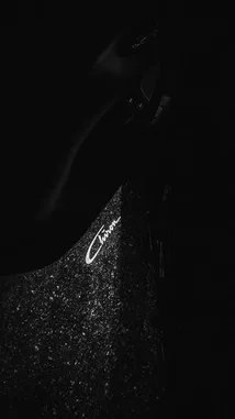 A close-up, cinematic shot focuses on the sparkling texture of Sabrina Carpenter's outfit, highlighting her name embroidered in elegant script. The dark, moody aesthetic creates intrigue, drawing attention to the details of her fashion statement. by @two with original sound
