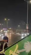 Witness the vibrant energy of a Saudi National Day celebration from the perspective of a participant waving the national flag. The scene unfolds on a bustling city street at night, illuminated by streetlights and car headlights, as festive crowds gather to celebrate their country's heritage. by @wedad_23g with عز الوطن 🇸🇦 by طلال