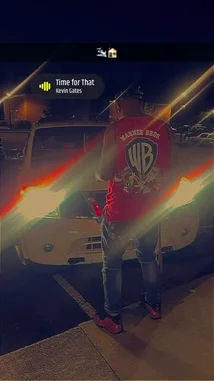 In this new visual, artist PLAYBOII Q stands confidently in a parking lot at night, wearing a red Warner Bros. shirt and pink sneakers. A car with its headlights on creates a dramatic lens flare effect. The scene is set to his track 'Time For That,' creating a cool, urban atmosphere. by @quezz.706 with Original Sound by Contains: Time for That - Kevin Gates