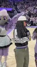 Singer Kehlani takes center stage during a WNBA game, performing for a packed arena. She walks across the court with a microphone, engaging with the crowd as fans hold up their phones to capture the moment. by @wnba with Original Sound by wnba