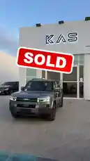 A sleek, modern KAS SUV is showcased in front of a dealership, with a prominent 'SOLD' graphic overlaying the scene. The vehicle is parked on a brick-patterned lot under a clear sky, highlighting its design and appeal. by @aaaaaa with كاريزما عاليه by '